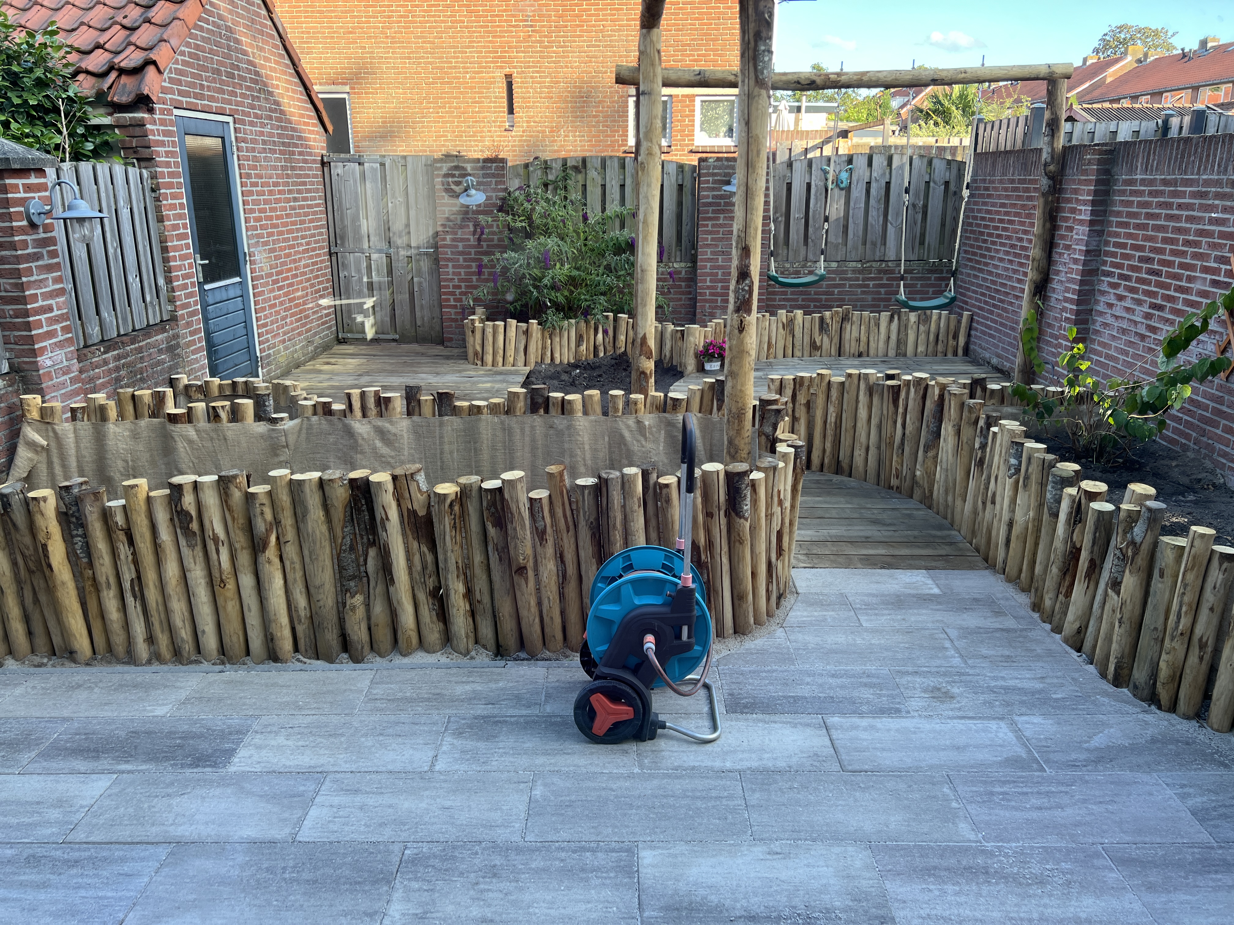 De tuin tijdens de aanleg — kastanjehouten paaltjes en vlonderplanken geven de nieuwe vormen aan